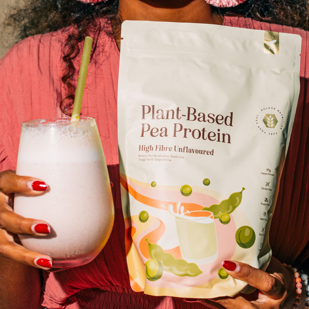 Person holding a glass of a pea protein shake and pea protein powder pouch