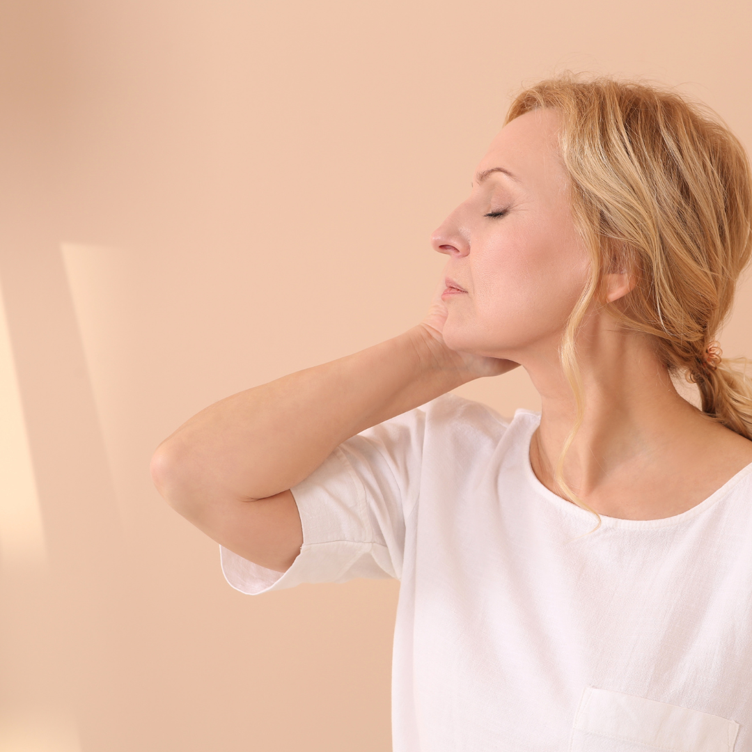 Woman with neck pain against a beige background