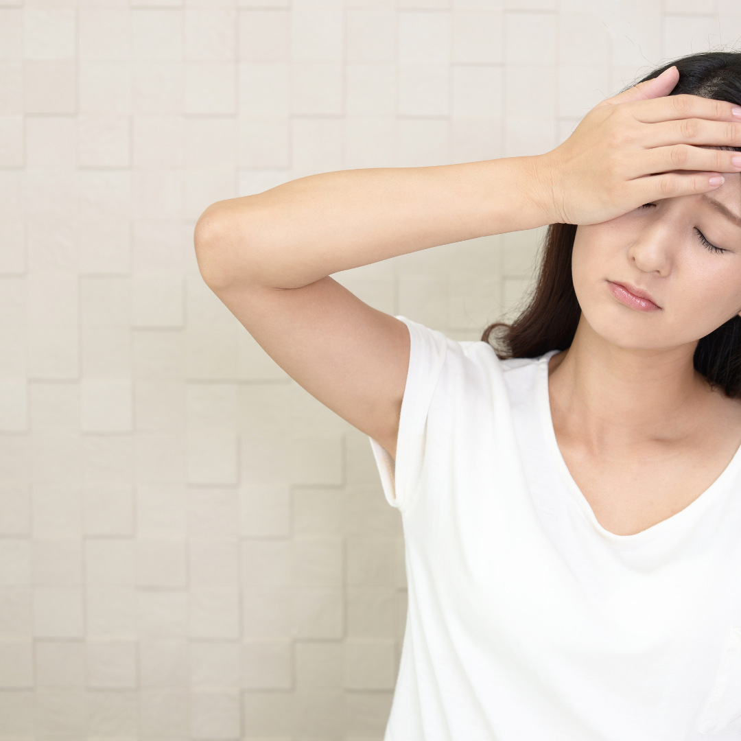 Woman in a white shirt with a hand on her face, possibly due to sweating or discomfort.