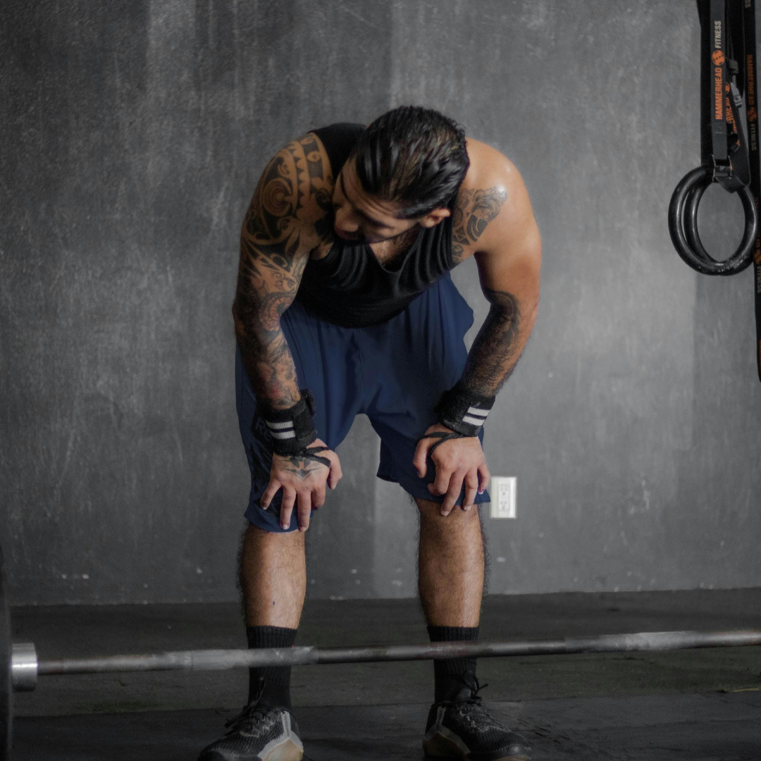 Man with tattoos preparing to lift weights in a gym setting