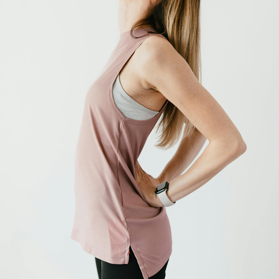 Woman wearing a pink tank top and black leggings on a white background