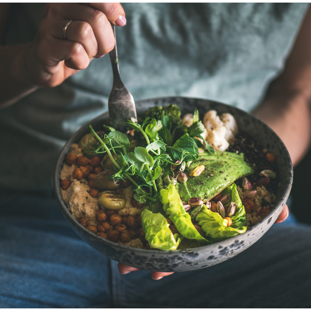 Person holding a bowl of salad with greens and chickpeas.