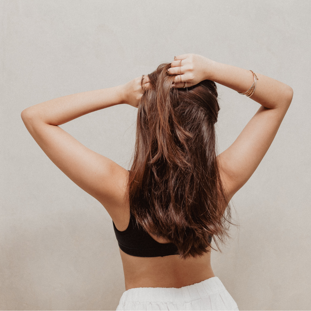 Woman with long brown hair standing against a plain background
